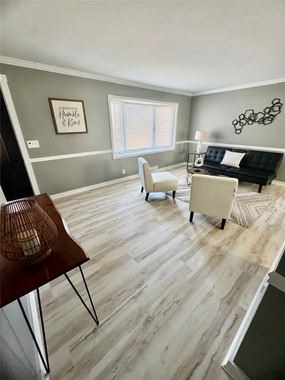 living area with baseboards, wood finished floors, and crown molding