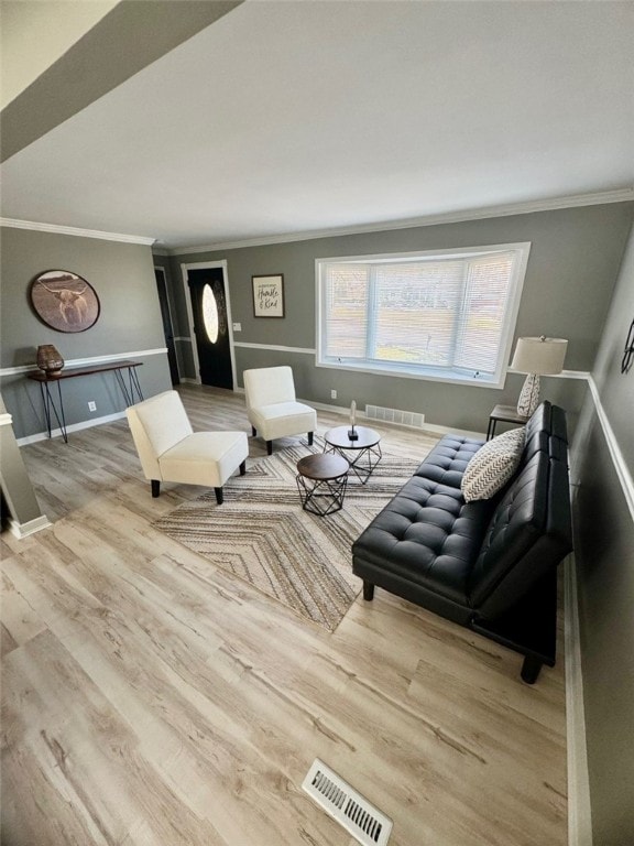 living room featuring visible vents, baseboards, wood finished floors, and crown molding