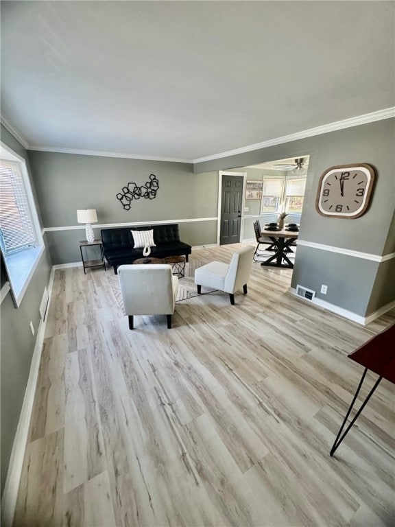 living room featuring visible vents, baseboards, wood finished floors, and crown molding