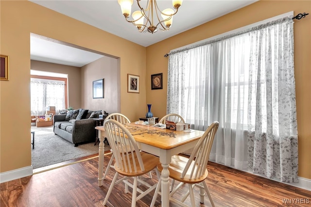 dining room featuring a chandelier, baseboards, and wood finished floors