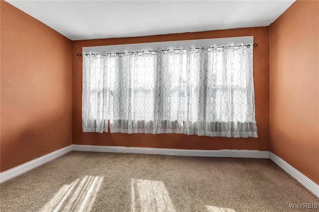 carpeted empty room featuring baseboards