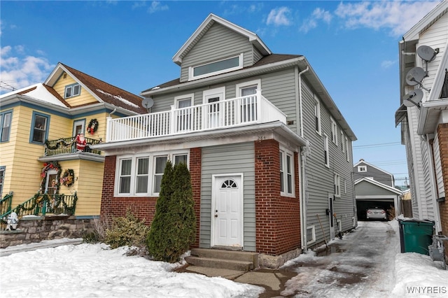 american foursquare style home featuring brick siding, entry steps, a garage, a balcony, and an outbuilding