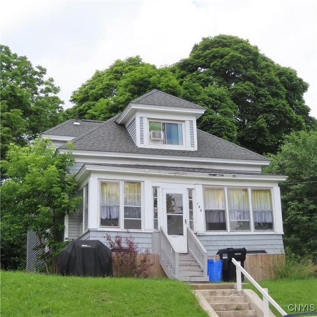 bungalow-style house featuring roof with shingles, a front yard, and entry steps