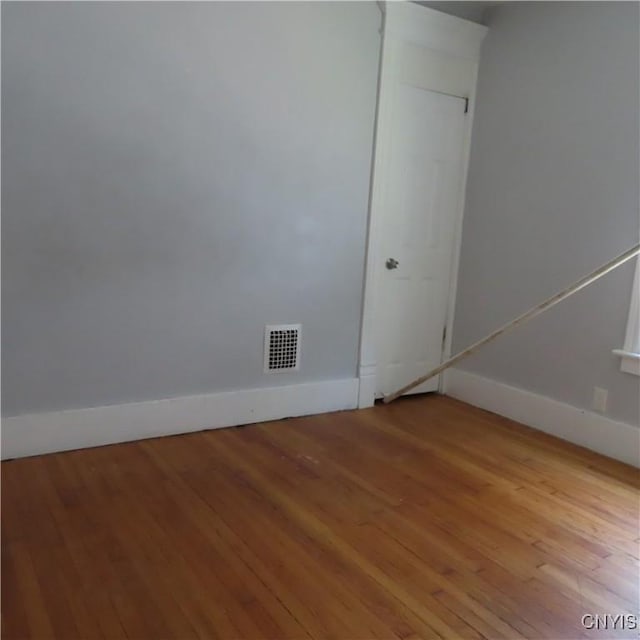 unfurnished room featuring visible vents, baseboards, and wood finished floors