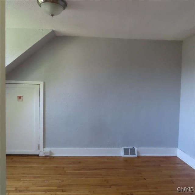 additional living space with visible vents, baseboards, lofted ceiling, and wood finished floors