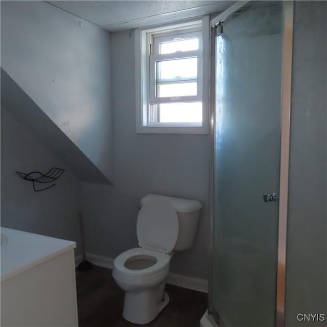 full bathroom with vanity, a shower stall, toilet, and baseboards