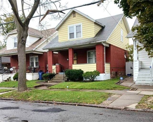 view of front facade featuring brick siding, covered porch, and roof with shingles