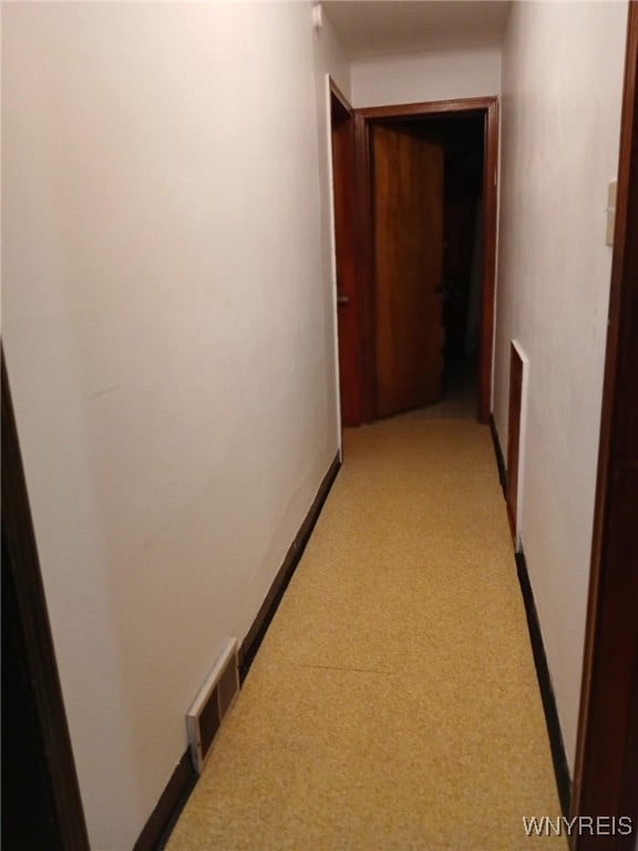 corridor featuring light carpet, visible vents, and baseboards