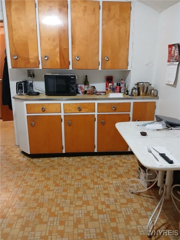 kitchen with brown cabinets, black microwave, and light countertops