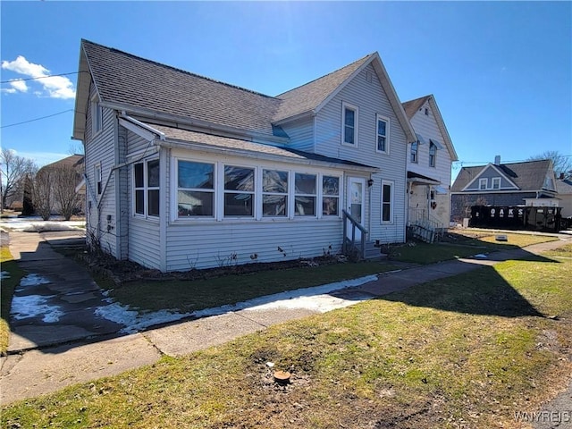 view of front facade featuring roof with shingles, a front yard, and entry steps