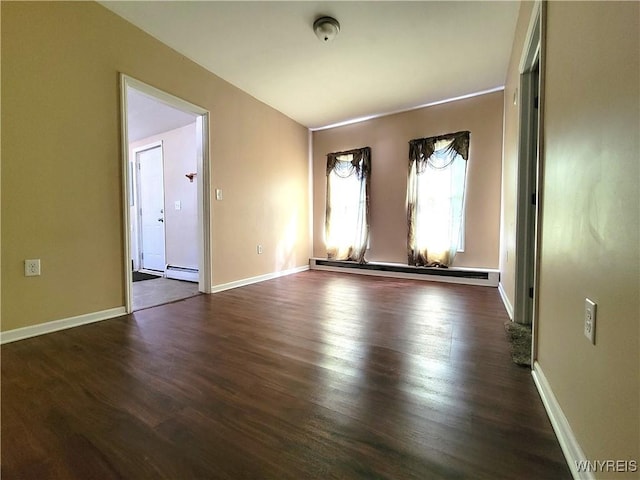 spare room with baseboards, dark wood-style flooring, and a baseboard radiator