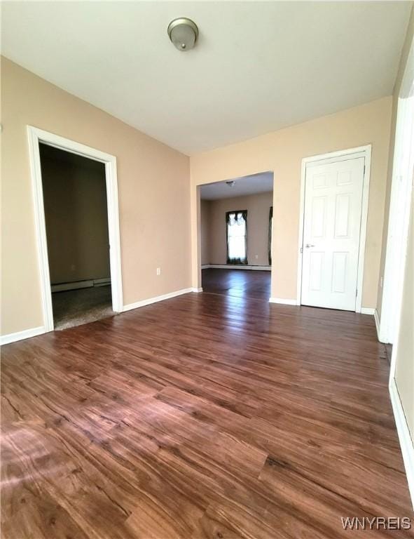 unfurnished room featuring dark wood finished floors, baseboards, and a baseboard heating unit