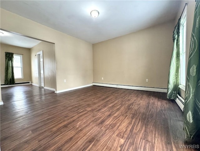 spare room with a baseboard radiator, baseboards, and dark wood-style flooring