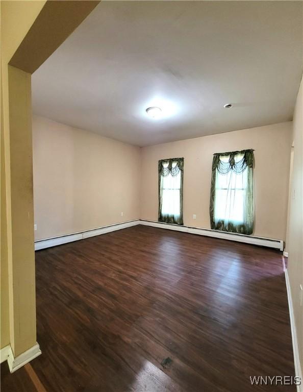 spare room featuring a baseboard radiator, baseboards, baseboard heating, and wood finished floors