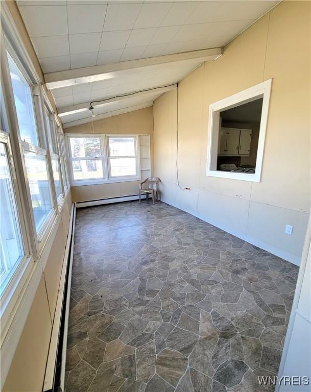 spare room with vaulted ceiling with beams, baseboard heating, and stone finish flooring