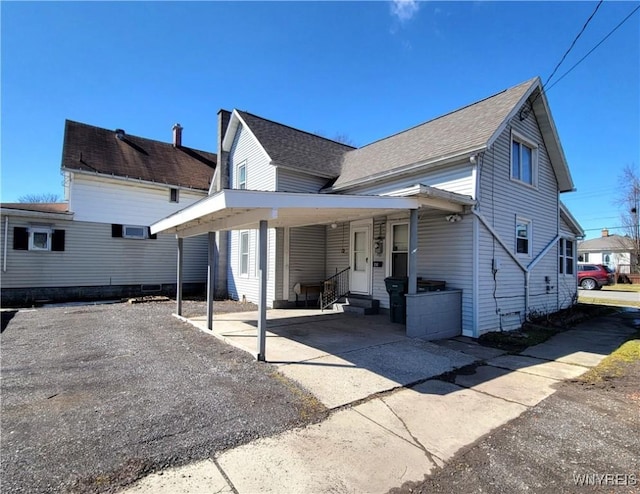 view of front of property with entry steps, a carport, and roof with shingles