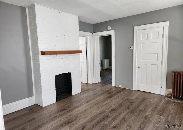 unfurnished living room with radiator, a fireplace, and wood finished floors