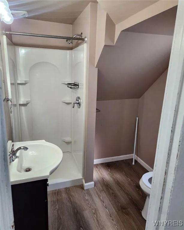 full bath with vanity, wood finished floors, baseboards, a shower stall, and toilet