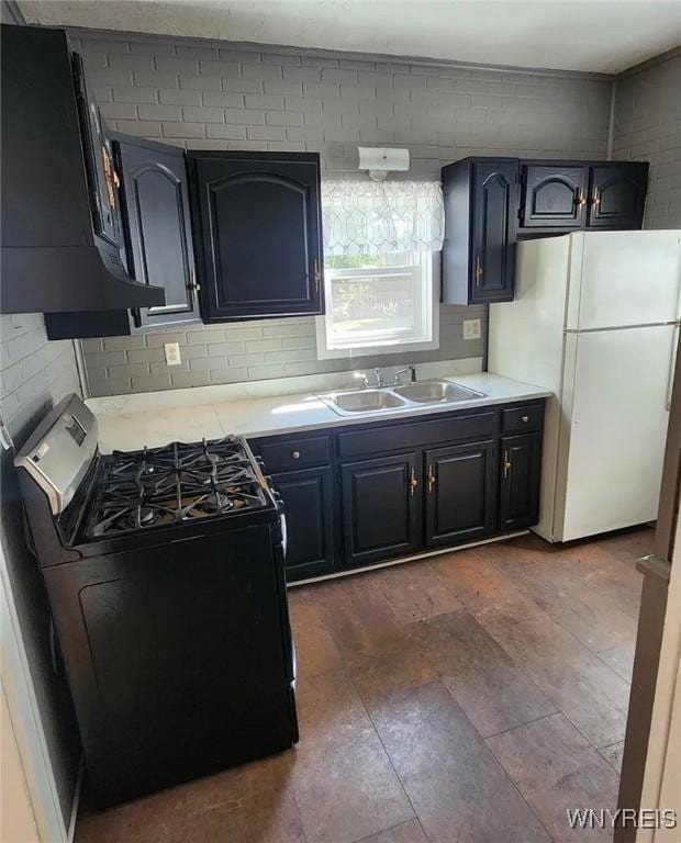 kitchen with black gas range, a sink, backsplash, freestanding refrigerator, and extractor fan