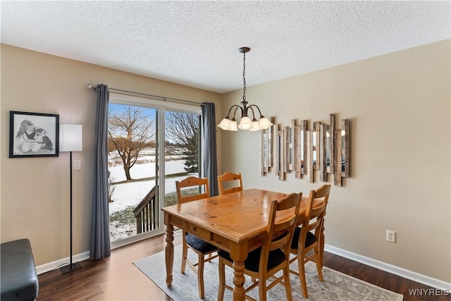 dining space with dark wood finished floors, a notable chandelier, a textured ceiling, and baseboards