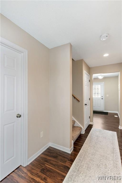 entryway featuring baseboards, dark wood-type flooring, and stairs