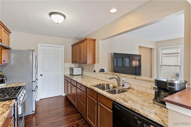 kitchen with stainless steel range with gas cooktop, dark wood finished floors, a sink, decorative backsplash, and dishwasher