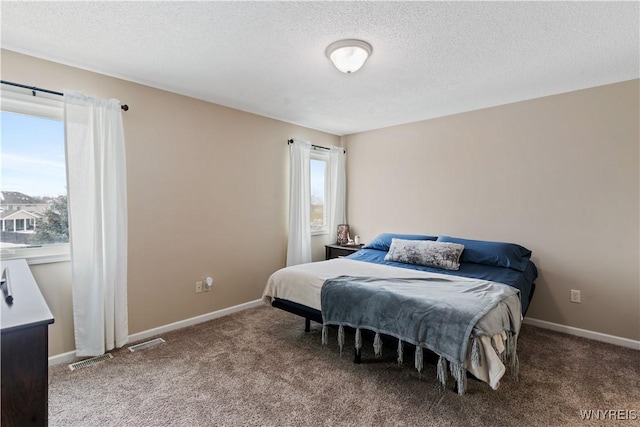 carpeted bedroom with multiple windows, a textured ceiling, and baseboards