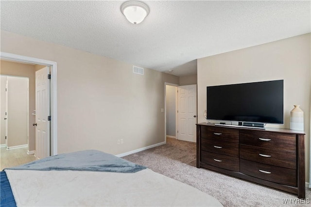 bedroom with light colored carpet, baseboards, visible vents, and a textured ceiling