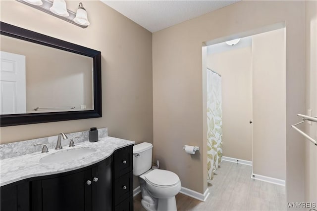 full bath with toilet, vanity, and baseboards