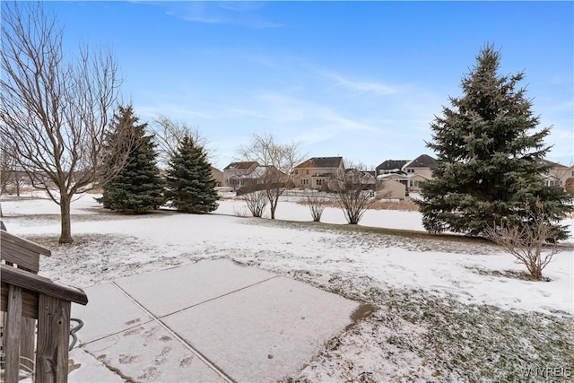 snowy yard featuring a patio area and a residential view