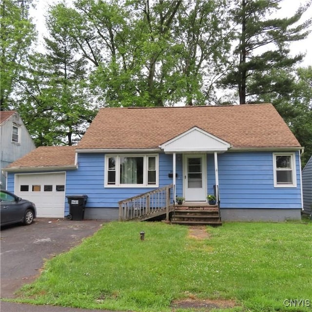 ranch-style home featuring a front yard, an attached garage, driveway, and a shingled roof