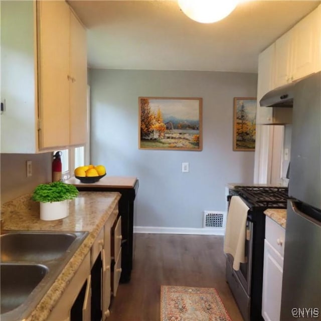 kitchen featuring visible vents, under cabinet range hood, appliances with stainless steel finishes, dark wood-style floors, and a sink