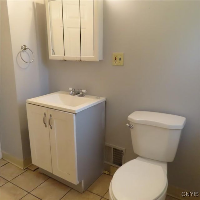 half bathroom featuring vanity, baseboards, visible vents, tile patterned floors, and toilet