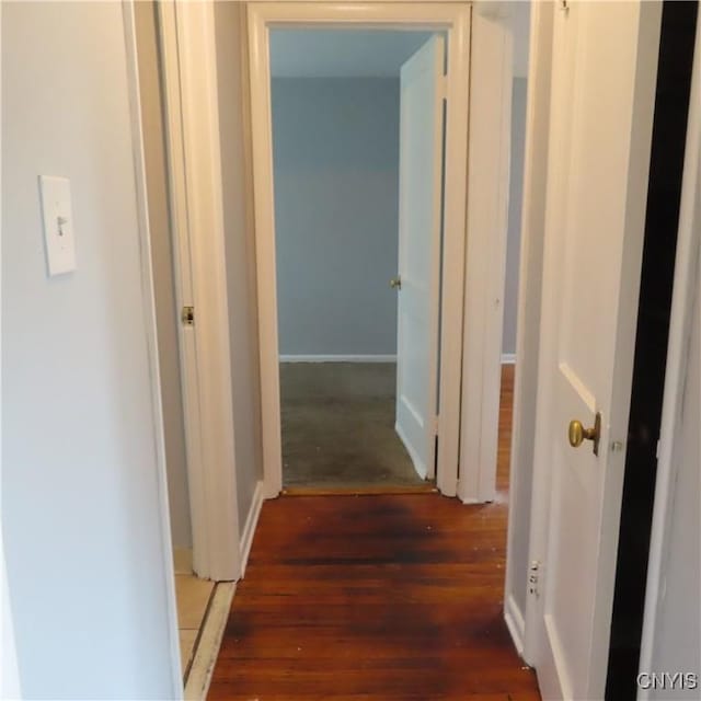 hall with baseboards and wood finished floors