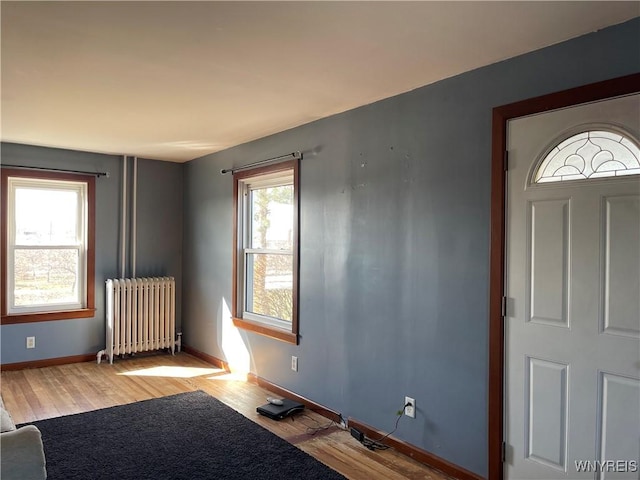 foyer entrance with light wood-style floors, baseboards, and radiator