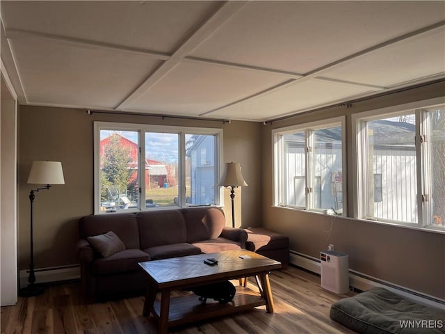 living area with a baseboard heating unit, plenty of natural light, and wood finished floors