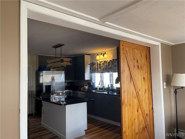 kitchen featuring dark countertops, a sink, radiator, a barn door, and dark wood-style flooring