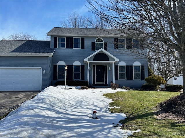 colonial inspired home featuring a garage, a lawn, driveway, and a shingled roof