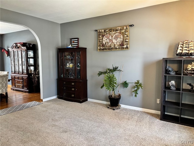 sitting room featuring arched walkways, baseboards, and carpet floors