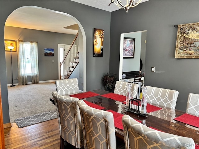 dining space with arched walkways, stairway, baseboards, and wood finished floors