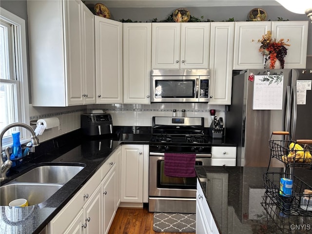 kitchen with a sink, white cabinets, a healthy amount of sunlight, and stainless steel appliances