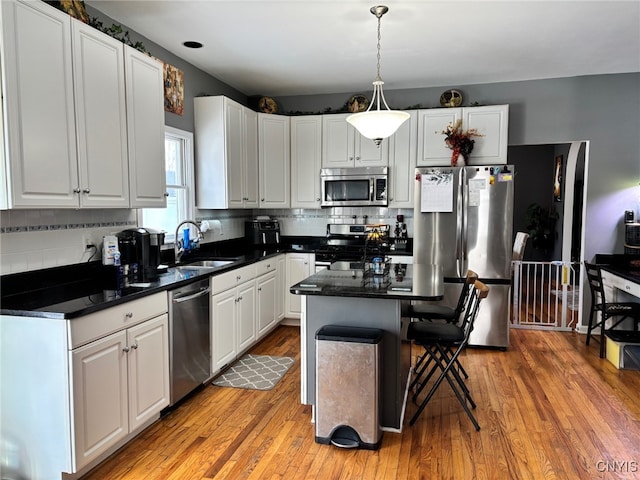 kitchen featuring a sink, dark countertops, light wood finished floors, and stainless steel appliances