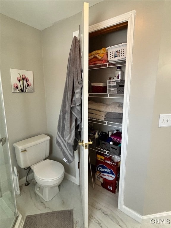 bathroom featuring toilet, baseboards, and marble finish floor