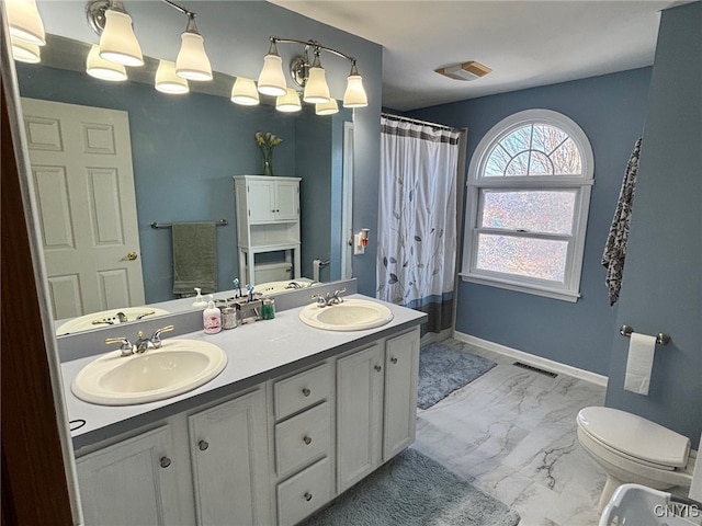 bathroom featuring a sink, baseboards, marble finish floor, and double vanity