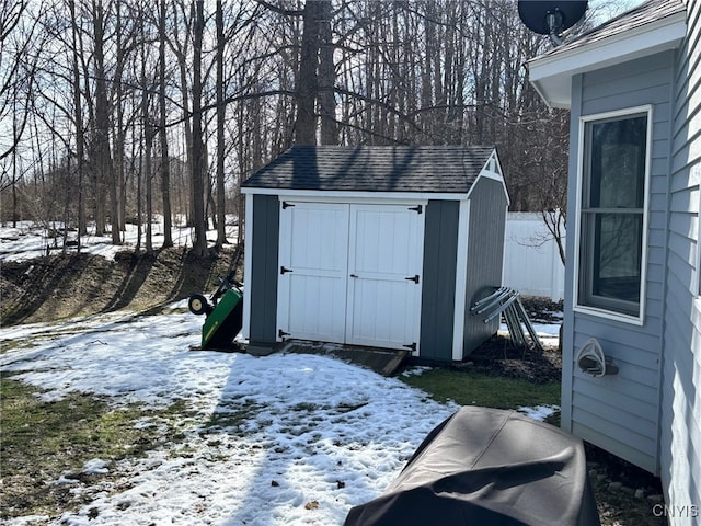 snow covered structure featuring an outdoor structure and a storage unit