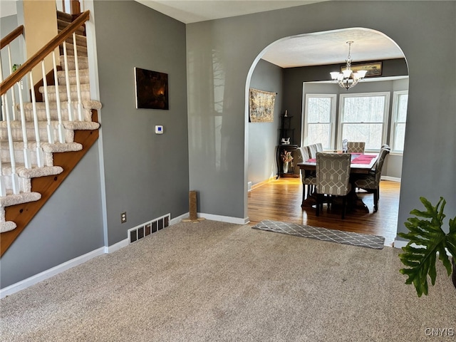 dining area featuring an inviting chandelier, arched walkways, visible vents, and baseboards