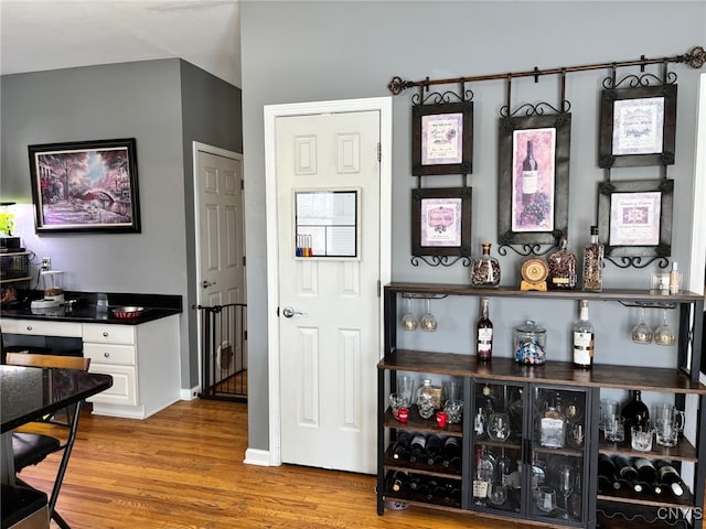 bar featuring a bar, baseboards, and wood finished floors