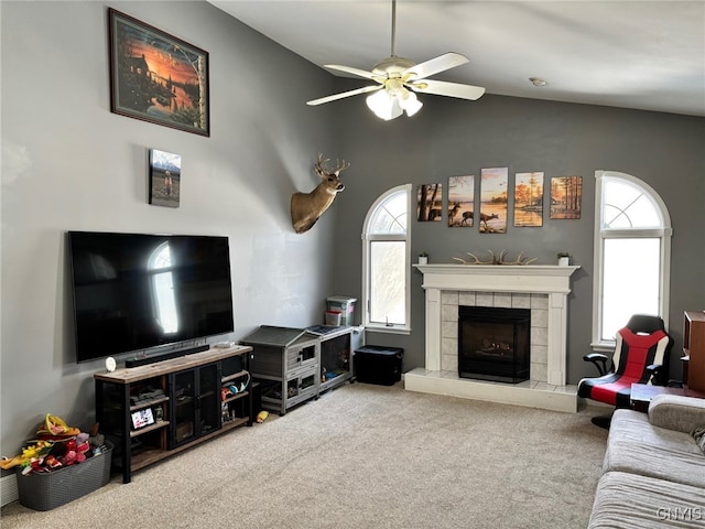 carpeted living area featuring lofted ceiling, a ceiling fan, and a tile fireplace