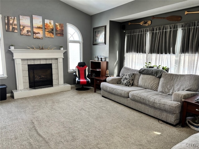 living area featuring carpet flooring, a tile fireplace, baseboards, and vaulted ceiling