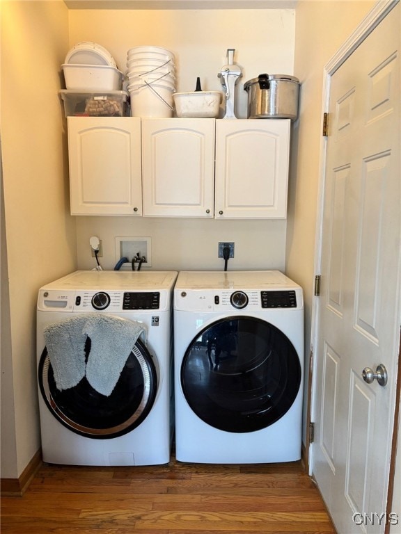 laundry area with cabinet space, washer and dryer, baseboards, and wood finished floors